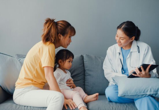 Doctor looking a woman with baby on sofa