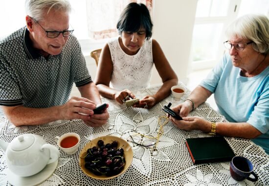 Older people looking at phones around a table